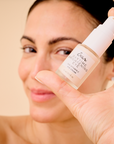 Image of a woman holding DAYTIME Brightening Eye on a cream background.